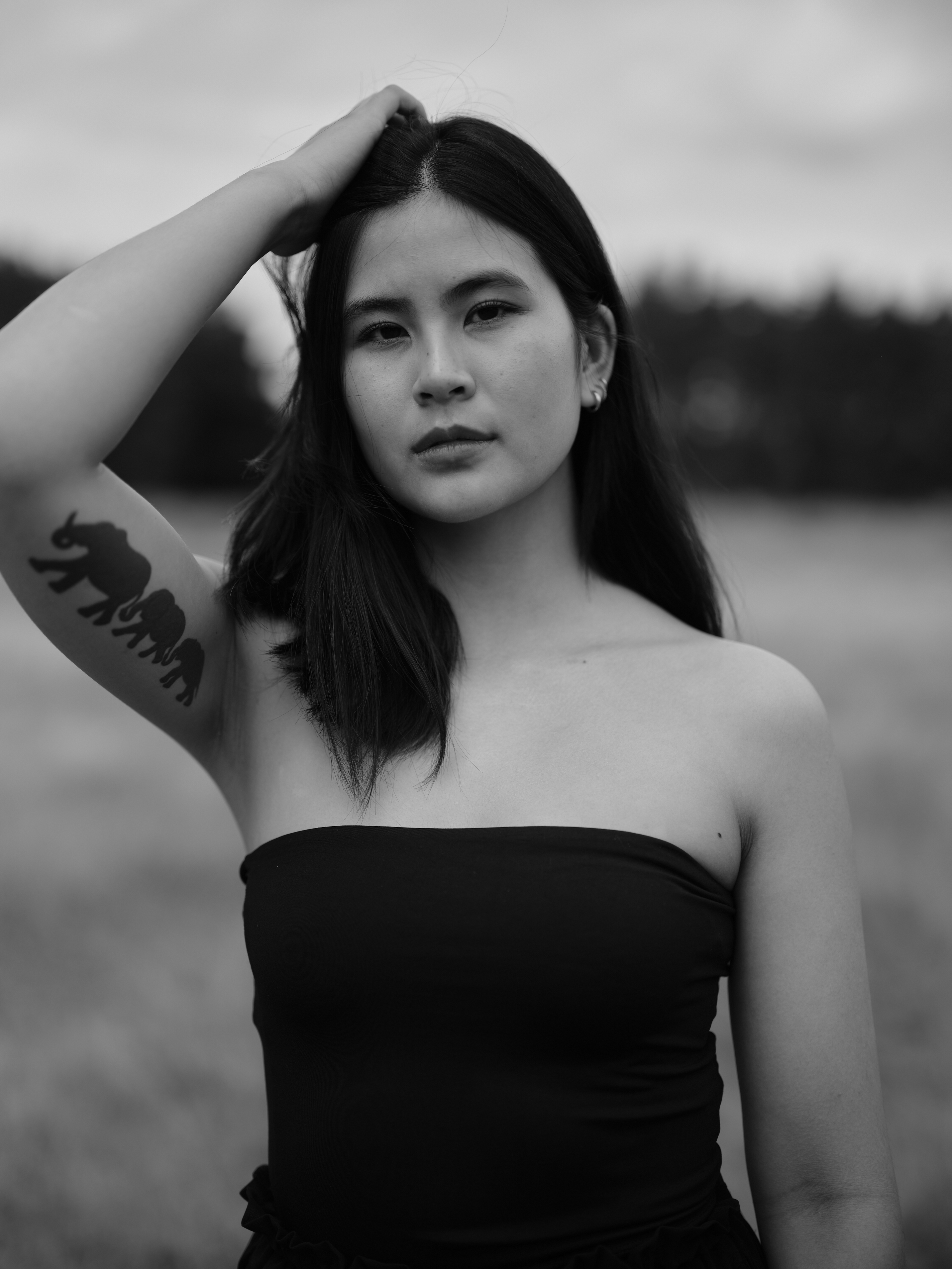 Junge Frau laechelt, schwarzweiss, schulterfrei, Elefant Tattoo am Arm