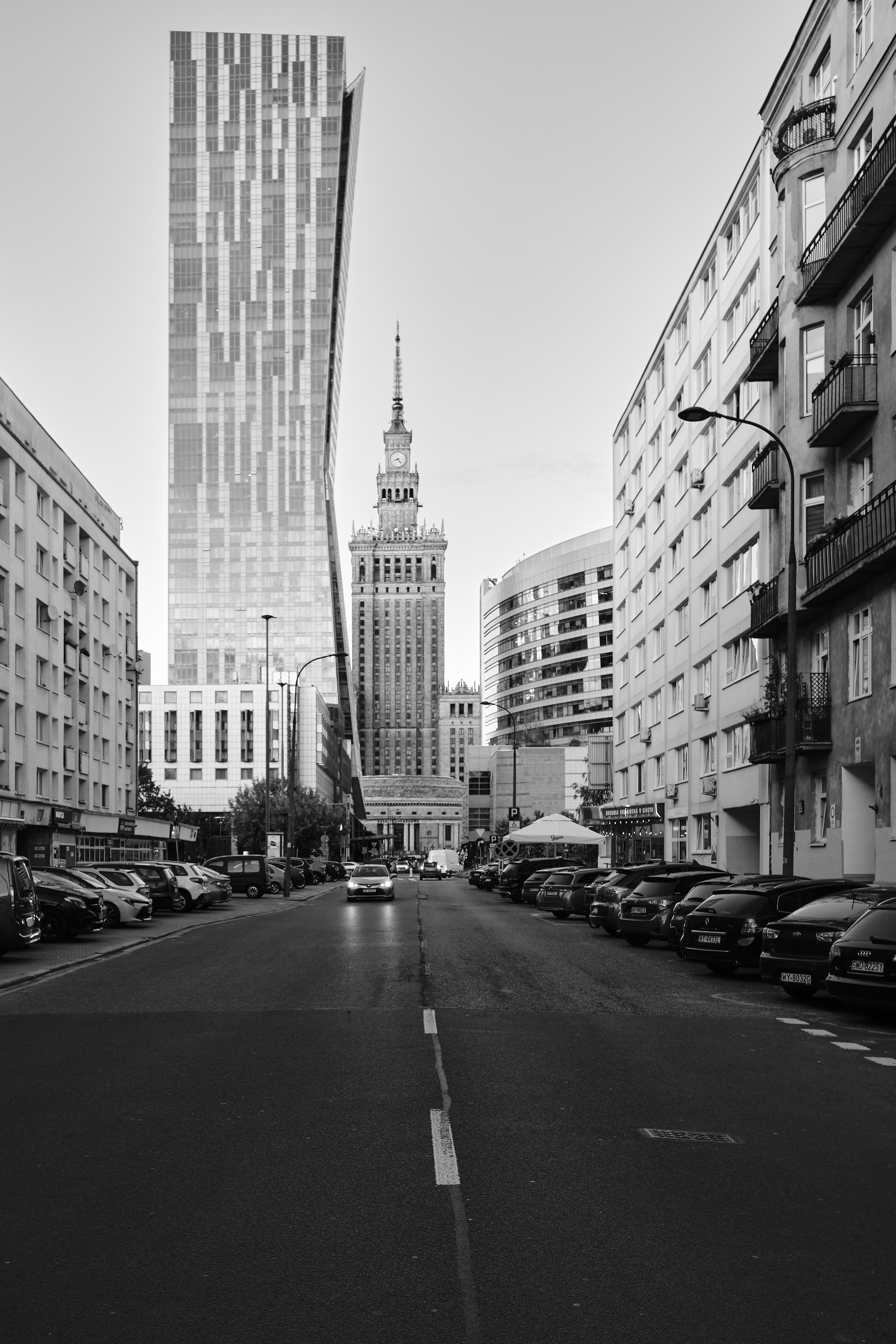 Schwarzweisse Strasse mit Autos, modernem Hochhaus und Uhrturm, ruhig