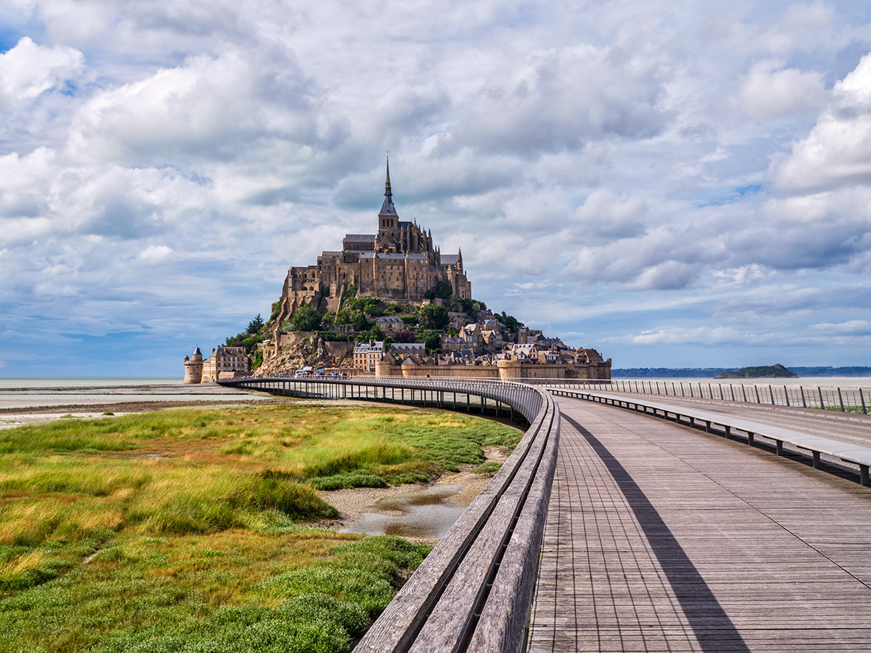 Der Mont Saint Michel mit Abtei auf einer Felseninsel unter wolkigem Himmel